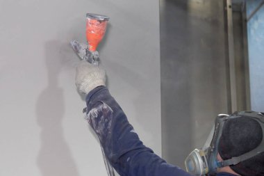 Bir adam toz boya metal ürünleri üretir.