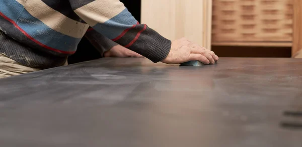 bir adam zımpara ile bir sünger ile siyah mat yüzey davranır.