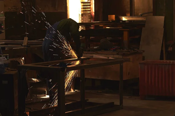 Çalışma şeklinde bir adam bir Bulgar ile metal testere keser.