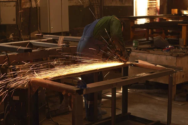 Çalışma şeklinde bir adam bir Bulgar ile metal testere keser.