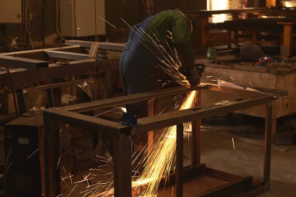 Um homem em forma de trabalho corta uma serra de metal com um búlgaro . — Fotografia de Stock