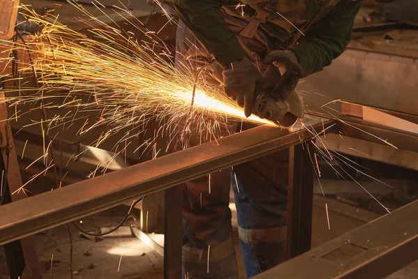 Um homem em forma de trabalho corta uma serra de metal com um búlgaro . — Fotografia de Stock