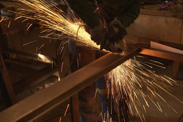 Um homem em forma de trabalho corta uma serra de metal com um búlgaro . — Fotografia de Stock