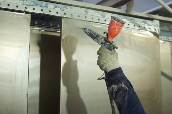 Bir adam toz boya metal ürünleri üretir.