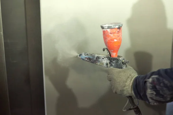 Bir adam toz boya metal ürünleri üretir.