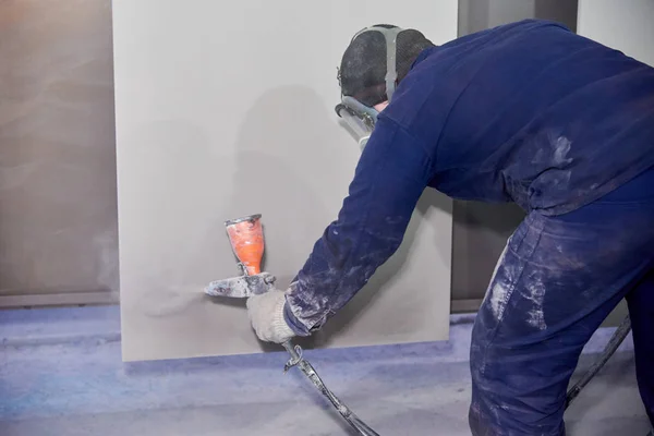 Bir adam toz boya metal ürünleri üretir.