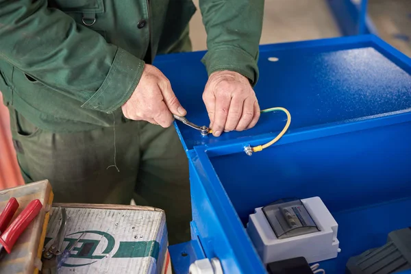 Bir adam trafo trafo merkezini toplar. Kirli bir cüppe içinde çalışmak.