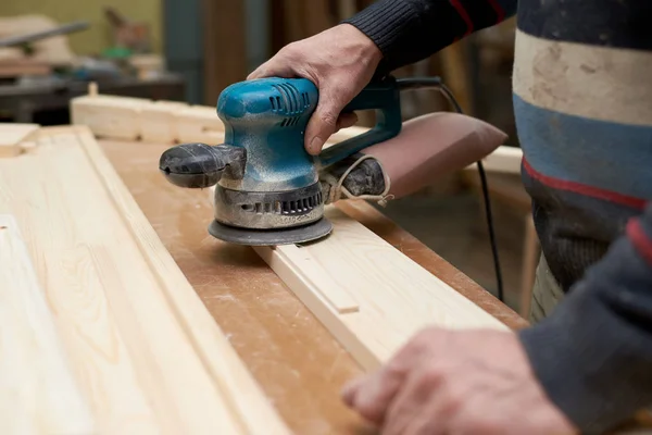 A man treats a wooden product with a grinding machine. Stock Image