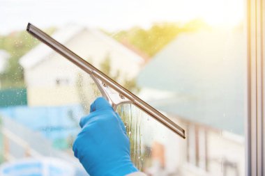 Kız eve bakan pencereyi yıkıyor, pencereye köpükle deterjan serpiştirir..