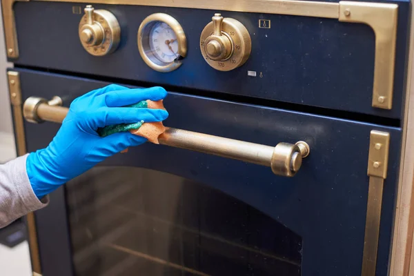 Kız bir sünger ve deterjan ile gaz sobası çalışma yüzeyini yıkar.