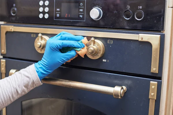 Kız bir sünger ve deterjan ile gaz sobası çalışma yüzeyini yıkar.