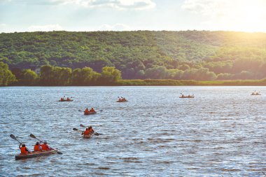 Nehirde yüzen kanolar güneş parlıyor.