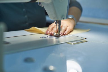 Bir kadın elektrikli dikiş makinesini diker..