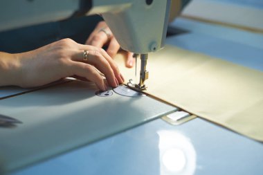 Bir kadın elektrikli dikiş makinesini diker..