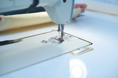 Bir kadın elektrikli dikiş makinesini diker..