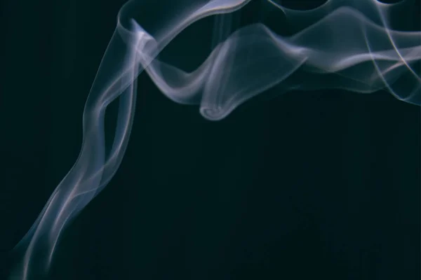 duman siyah bir arka plan üzerinde farklı desenler etrafında wriggles.