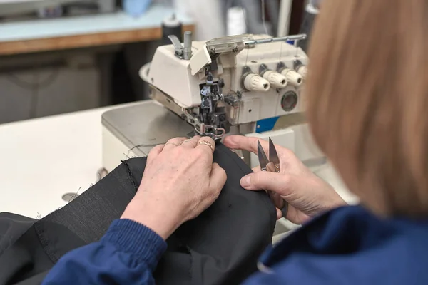 Bir kadın elektrikli dikiş makinesini diker..