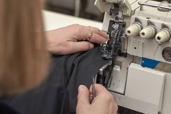 Bir kadın elektrikli dikiş makinesini diker..