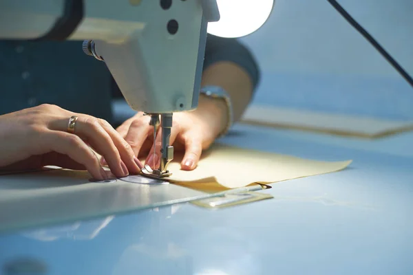 Bir kadın elektrikli dikiş makinesini diker..