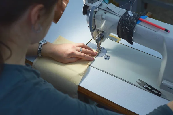 Bir kadın elektrikli dikiş makinesini diker..