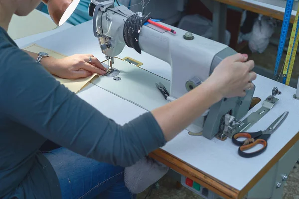 Bir kadın elektrikli dikiş makinesini diker..