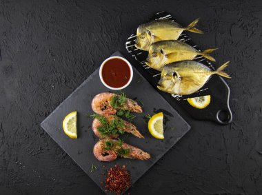 Haşlanmış karides ve limon, yeşillik ve sos ile füme balık ahşap bir arka plan üzerinde.