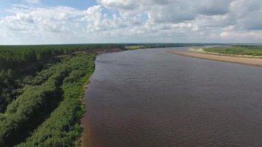 Kamera, yaz aylarında büyük bir nehir üzerinde uçar. İğne yapraklı orman nehir kıyısında yetişen