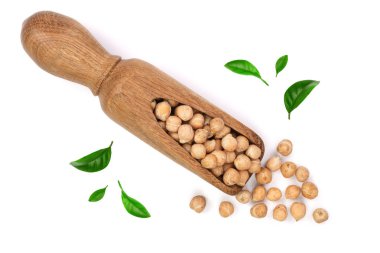 Yeşil yaprakları ile süslenmiş beyaz arka plan üzerinde izole bir tahta kaşık kuru ham organik nohut. Üstten görünüm