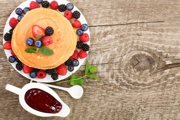 Pancakes stack with different berries on old wooden background with copy space for your text. Top view. Flat lay — Stock Photo, Image