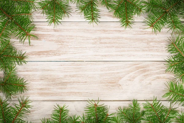 Marco de Navidad hecho de ramas de abeto sobre un fondo de madera claro — Foto de Stock