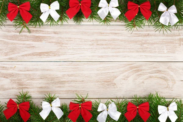 圣诞框架由冷杉树枝装饰弓在一个轻的木制背景 — 图库照片