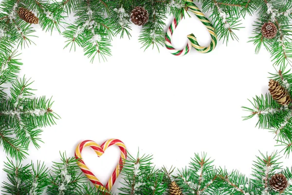 Moldura de Natal de ramo de árvore de abeto com bastões de doces e neve isolada no fundo branco com espaço de cópia para o seu texto — Fotografia de Stock