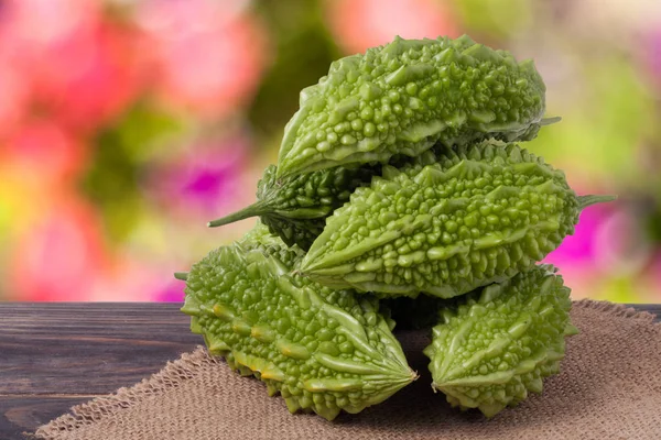 Heap of bitter melon or momordica on wooden table with blurred background — Stock Photo, Image