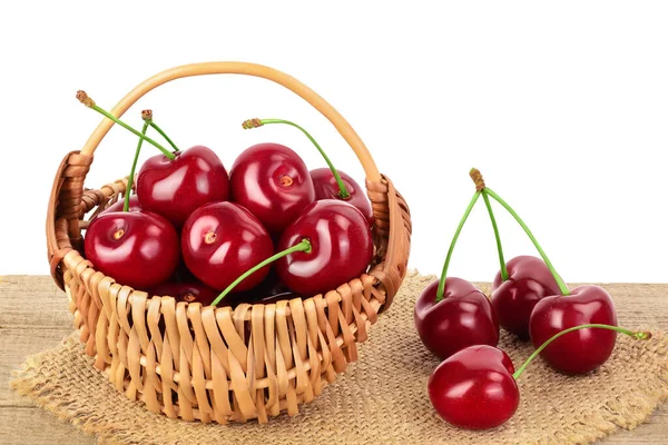 Cereza roja dulce en una canasta de mimbre sobre mesa de madera aislada sobre fondo blanco con camino de recorte y plena profundidad de campo — Foto de Stock