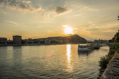 Budapeşte waterfront kentsel city scape ile Tuna Nehri günbatımı zamanında gemiler ve güneş bakıyor