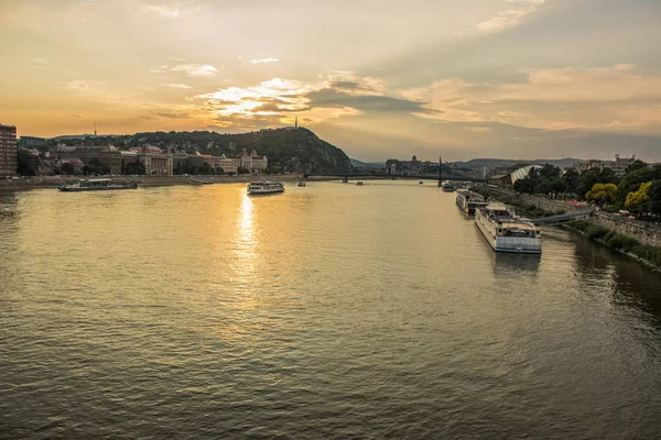 Budapeşte waterfront kentsel city scape ile Tuna Nehri günbatımı zamanında gemiler ve güneş bakıyor