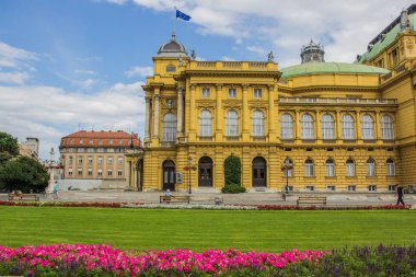 ön planda renkli çiçek yatağı ile Opera Evi Bina mimarisi sarı cephe