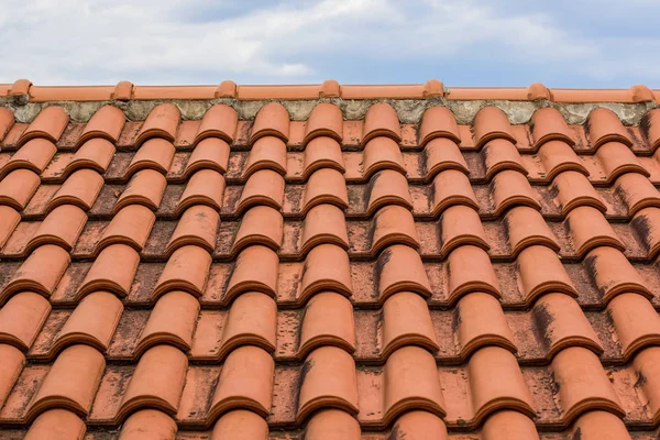 帯状疱疹の赤い家の屋根の前景のテクスチャとコピーまたはテキストのための空のスペースと灰色の曇り空の背景の概念 — ストック写真