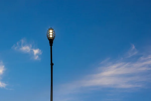 street lantern yellow illumination from below on evening blue sky background city urban photography concept with empty copy space for text