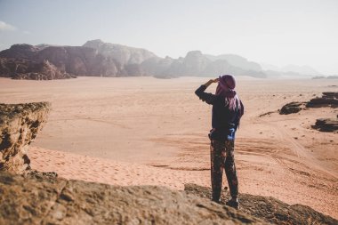 seyahat kadın kameraya geri kalmak ve dramatik Wadi Rum Ürdün çöl manzara manzara dünyaca ünlü miras turistik yer yüzüne yakın elinin altından bakarak  