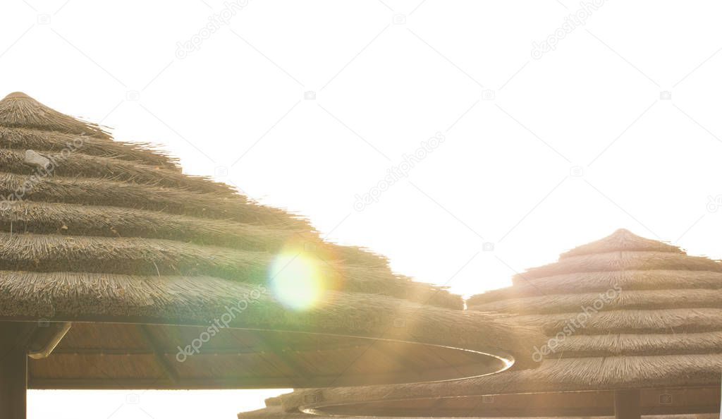 unfocused abstract straw umbrella in sea beach i sun glares light panorama foreshortening with overexposed white sky, summer vacation concept picture with empty copy space for your text