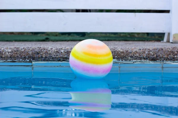 swimming pool and white fence unfocused background space for rest in free time with ball on water surface