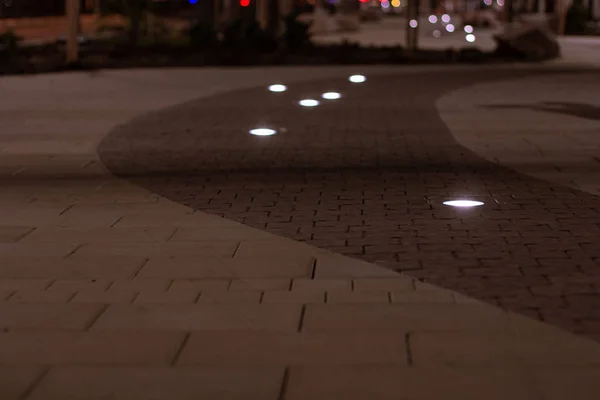 夕暮れ時の照明で柔らかい焦点ランプイルミネーションを持つ夕方の街路舗装道路 — ストック写真