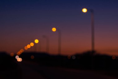koyu mavi ve turuncu romantik renkler ve sokak fenerleri ile gün batımından sonra gece alacakaranlık unfocused soyut kavram resmi ülke kenarı karayolu boyunca sarı aydınlatma