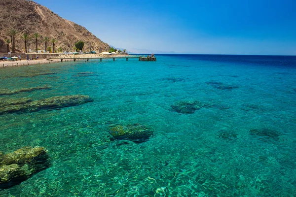 红海风光景观景观美丽的热带避暑胜地海蓝宝石透明水与珊瑚礁底部和沙漠山脉和码头与人的背景 — 图库照片
