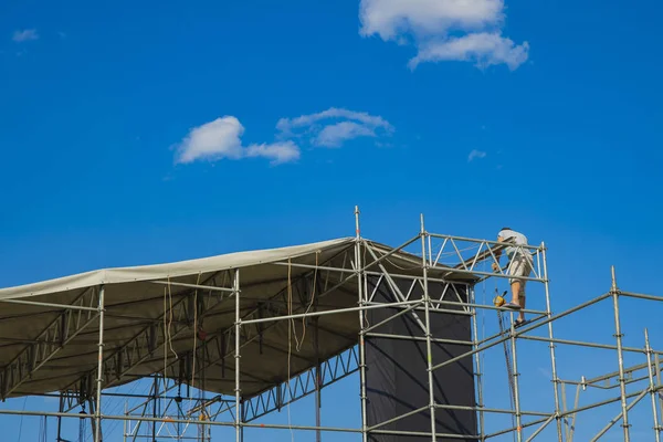 stage construction process with worker, blue sky background, copy space