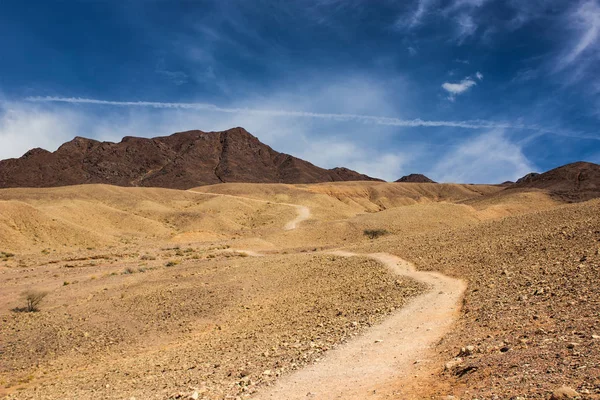 vadi ve iz ön plan ve dağ sırtı ve canlı mavi gökyüzü beyaz bulut arka plan ile pitoresk çöl çorak sahne manzara 