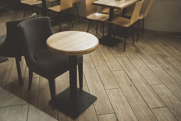 minimalism hipster style cozy cafe interior with small wooden table and soft black chair empty furniture, stylish tile floor