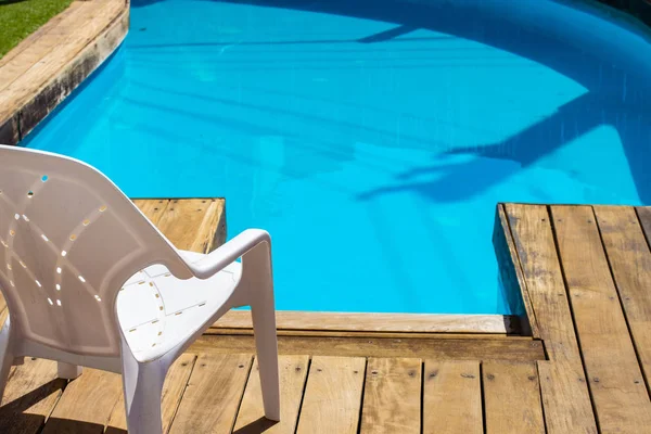 hotel free space for relaxation in summer vacation season time with white plastic chair near swimming pool blue water on wooden deck floor