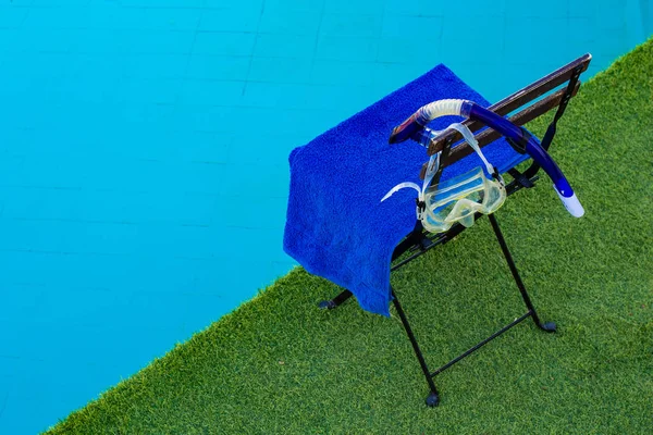 緑の草の合成床のスイミングプールの青い水の近くにタオルとシュノーケリングマスクと椅子 フリータイムコンセプト画像でライフスタイルの趣味の活動 — ストック写真
